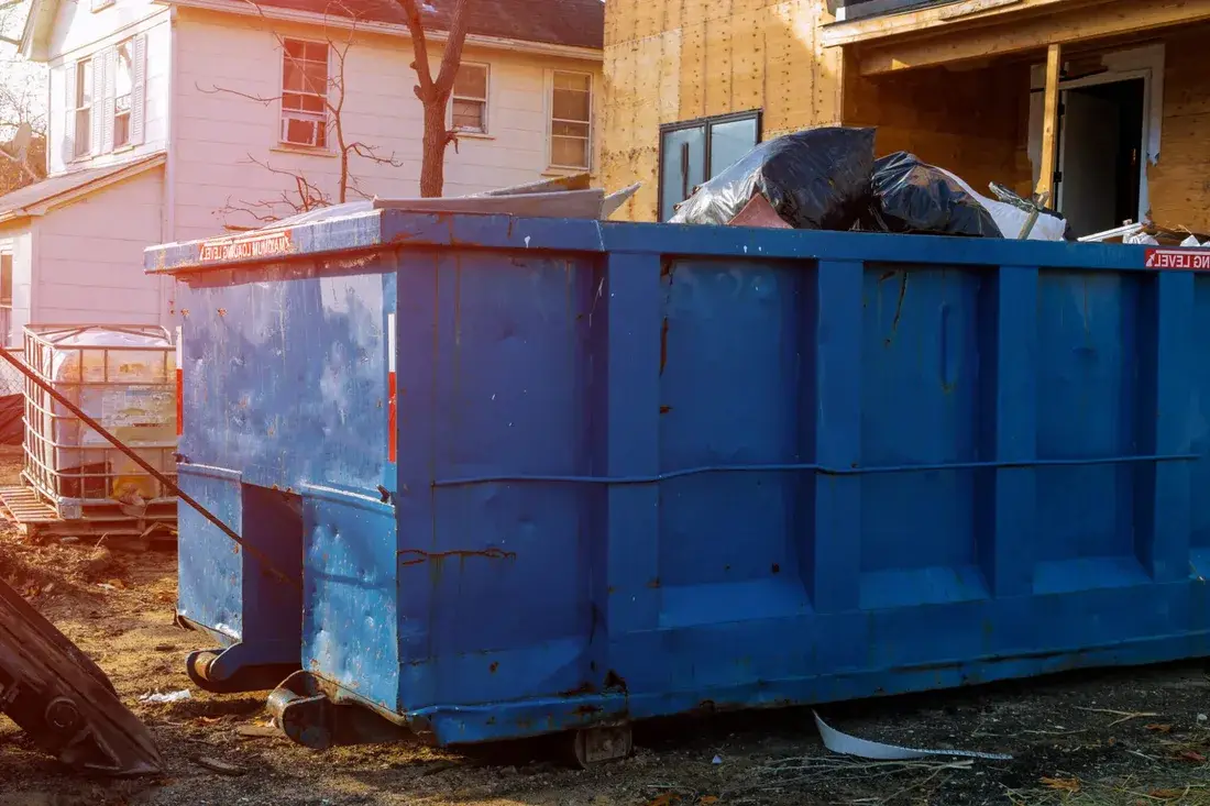 Roll-off dumpster loaded with roofing shingles on a job site
